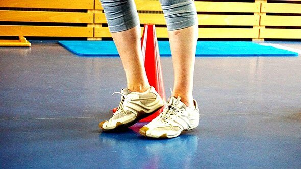 Blick auf die Beine einer Person in einer Turnhalle.