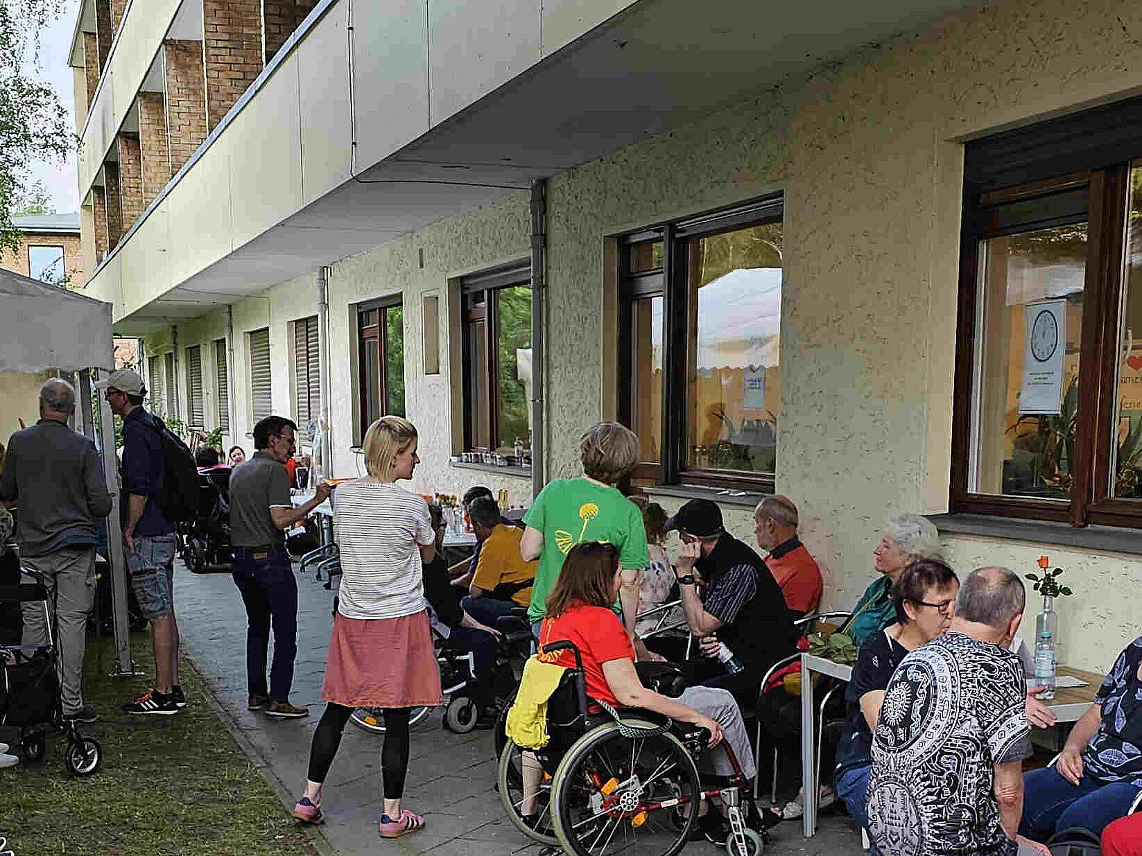 Menschen stehen und sitzen auf einer Rasenfläche.