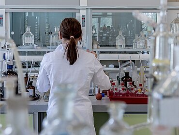 Eine Frau im weißen Kittel, die in einem Labor arbeitet.
